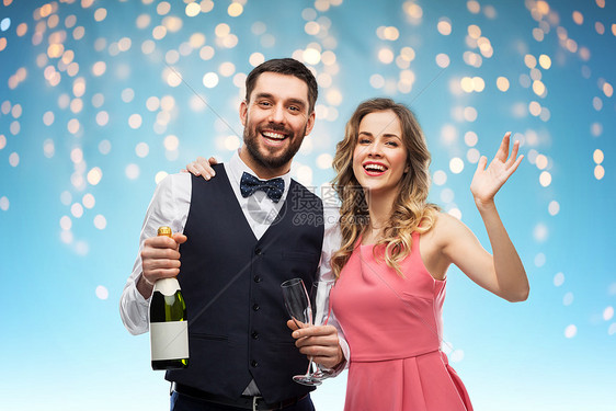 庆祝人们的幸福的夫妇与瓶香槟眼镜节日灯的蓝色背景幸福的夫妇带着瓶香槟眼镜图片