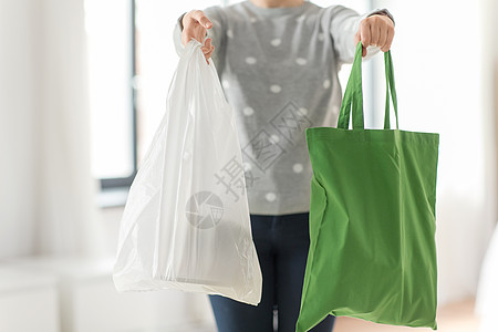 消费主义生态友好的妇女持有可重复用的帆布手提包,用于食品购物塑料袋的灰色背景带手提包购物塑料袋的女人图片