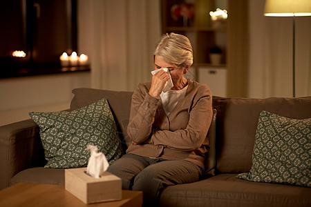 高级妇女家里用纸巾擦拭眼泪晚上哭泣的高级妇女用纸巾擦眼泪背景图片