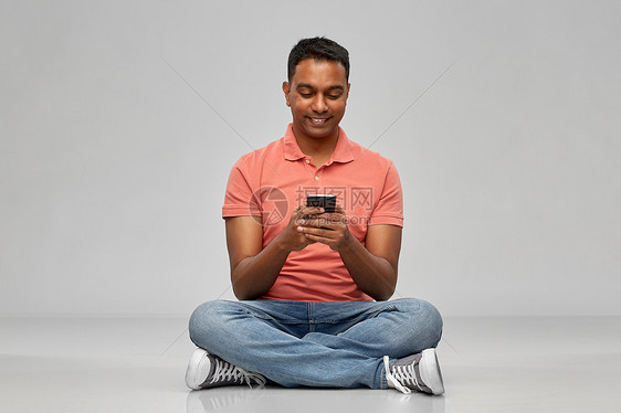 技术,通信人的快乐的印度男子用智能手机灰色背景快乐的印度男人用智能手机图片