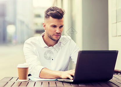 少儿计算机商业,技术人的年轻人带笔记本电脑咖啡杯城市街咖啡馆带笔记本电脑咖啡的男人城市咖啡馆背景