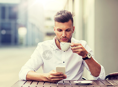 商业,技术人的年轻人有智能手机,喝咖啡短信城市咖啡馆有智能手机的男人城市咖啡馆喝咖啡图片