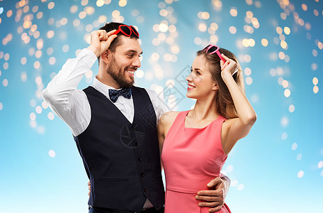 情人节,爱人的幸福的夫妇心形太阳镜假日灯蓝色背景戴着心形太阳镜的幸福夫妇图片