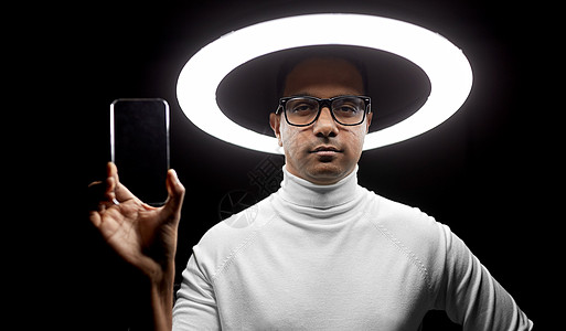 未来的技术虚拟现实印度男子戴着透明智能手机的眼镜,黑色背景下白色照明戴眼镜的男人照明下戴着智能手机图片