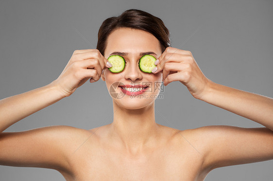 美容,护肤排美丽的女人制作黄瓜眼罩灰色背景美丽的女人用黄瓜做眼罩图片