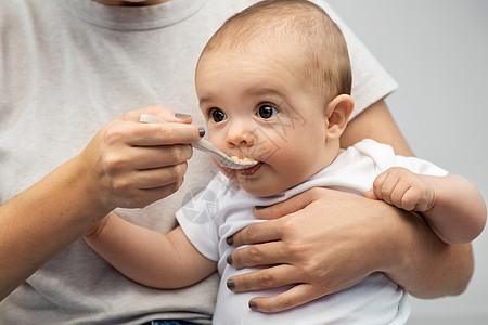 孩子,吃食物的密切母亲用勺子喂养小婴儿用勺子喂小宝宝来亲近妈妈图片