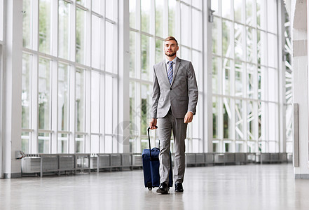 商务旅行,企业人的年轻商人带着旅行袋沿着办公楼或机场步行商人带着旅行袋沿着办公室走图片