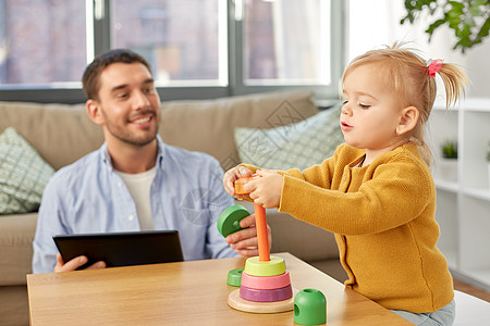 家庭,父亲人的快乐的父亲与平板电脑电脑小女儿玩金字塔玩具家里父亲平板电脑婴儿女儿家图片