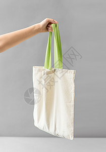消费主义生态友好的手可重复用的帆布袋,用于灰色背景下的食品购物手持可重复用的帆布袋进行食品购物背景图片