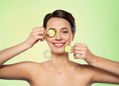 美容,护肤排美丽的女人制作黄瓜眼罩石灰绿色的自然背景美丽的女人用黄瓜做眼罩背景图片