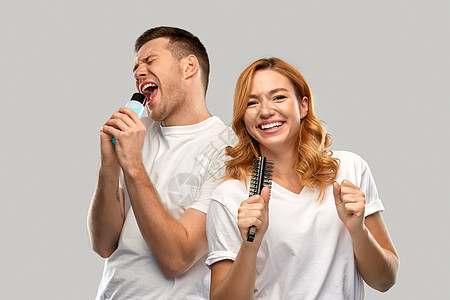 人际关系人的幸福的夫妇白色T恤夫妇唱歌的梳子洗剂瓶灰色背景快乐的夫妇唱歌给梳子乳液背景图片