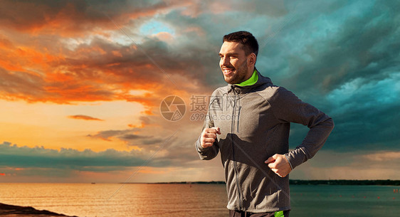 健身,运动人的快乐的年轻人跑过海洋日落天空的背景快乐的年轻人跑过大海日落的天空图片