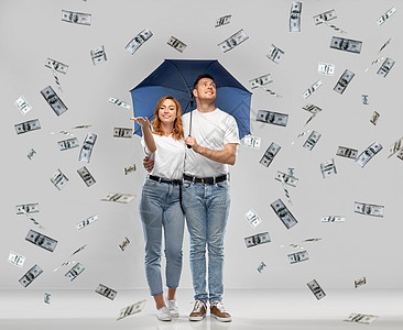 金融,安全保护幸福的微笑夫妇穿着白色T恤,伞站金钱雨下灰色背景幸福的夫妇带着雨伞站着钱雨图片