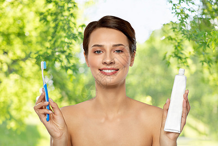 口腔卫生,牙科护理健康理念微笑的女人用牙刷牙膏清洁牙齿绿色自然背景微笑的女人用牙刷清洁牙齿图片