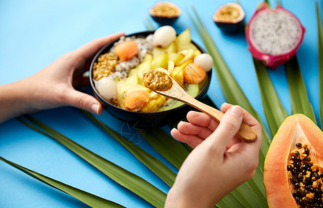 食物,夏天健康的饮食手与同的异国水果混合碗与木勺绿色风扇棕榈叶蓝色背景用异国水果木勺混合的手图片