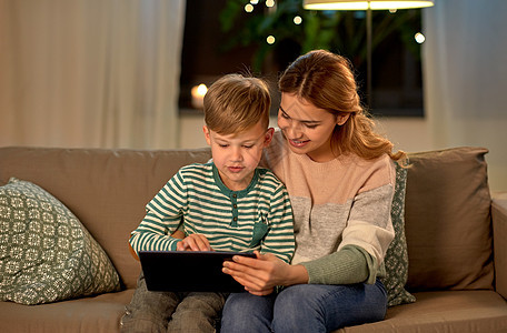 家庭技术人的快乐的母亲小儿子坐沙发上,家用平板电脑母子家里用平板电脑图片