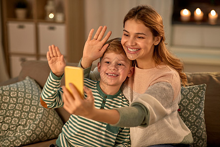 家庭,爱人的快乐的微笑母亲小儿子家里用智能手机自拍母子家里用智能手机自拍图片