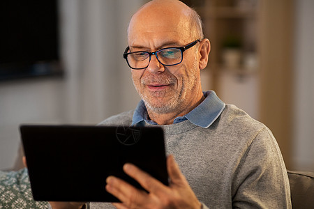 技术,老年人人的快乐的秃顶老人与平板电脑坐沙发上,晚上家家里有平板电脑的快乐老人图片