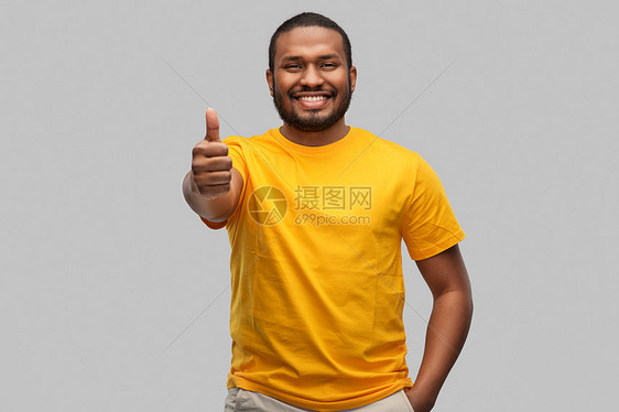 手势人的微笑的年轻非洲裔美国人穿着黄色T恤,灰色背景上竖起大拇指微笑的非裔美国人竖起大拇指图片