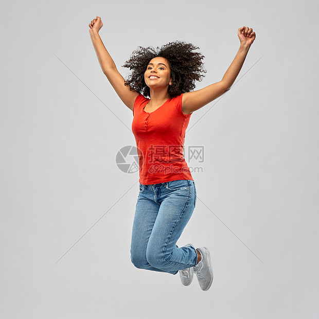 自由,运动人的快乐的微笑非裔美国年轻妇女跳跃空中与举起的手臂灰色的背景微笑的非裔美国女男子空中跳跃图片