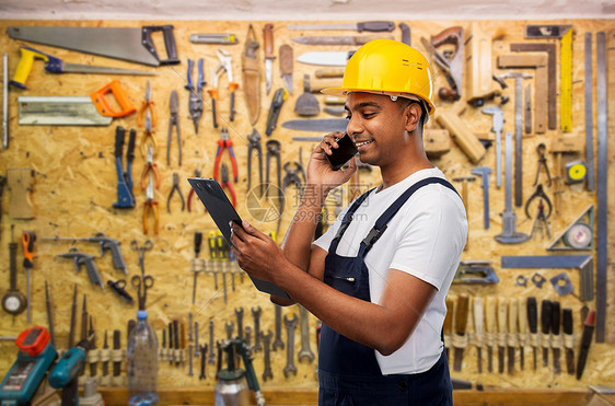 专业,建筑建筑快乐的微笑印度工人或建筑工人头盔与剪贴板呼吁智能手机工作工具的背景印度建筑工人用剪贴板打电话图片