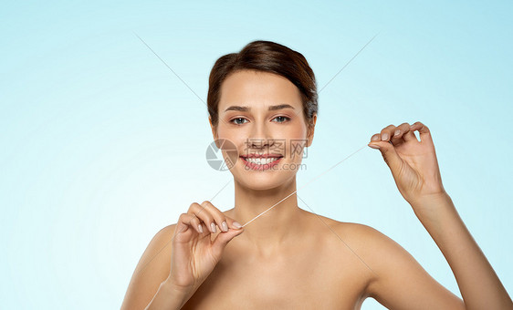 口腔卫生,牙科护理健康快乐的年轻妇女用牙线清洁牙齿的蓝色背景快乐的年轻女人用牙线清洁牙齿图片