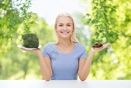 饮食,食物饮食快乐的微笑女人选择西兰花甜甜圈的绿色自然背景微笑的女人选择西兰花甜甜圈图片