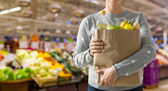 购物,健康饮食生态友好的妇女与纸袋充满食物超市的背景用装满食物的纸袋把女人关起来图片
