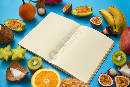 食物,饮食健康饮食同的异国水果围绕笔记本或日记,空页蓝色背景带空页的笔记本周围的异国水果图片