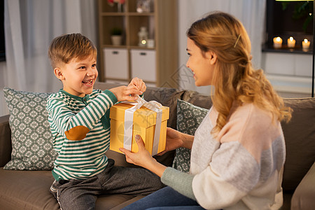 母亲节,假期家庭观念微笑的母亲晚上家给她快乐的小儿子送礼物母亲家里给她的小儿子送礼物背景图片