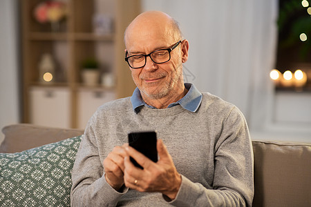技术,人沟通的快乐的微笑秃顶老人家里的智能手机短信快乐的老人家用智能手机发短信图片