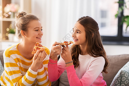 人,食物友谊的快乐的十几岁的女孩家吃比萨饼快乐的十几岁的女孩家吃披萨图片