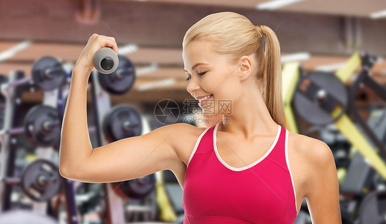 运动,健身人们快乐的微笑年轻运动女与轻哑铃健身房的背景上锻炼快乐的年轻女人戴着哑铃健身房锻炼图片
