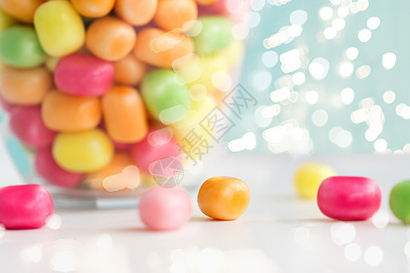 食物,糖果糖果的玻璃罐与彩色糖果滴灯光上的蓝色背景把五颜六色的糖果滴桌子上图片