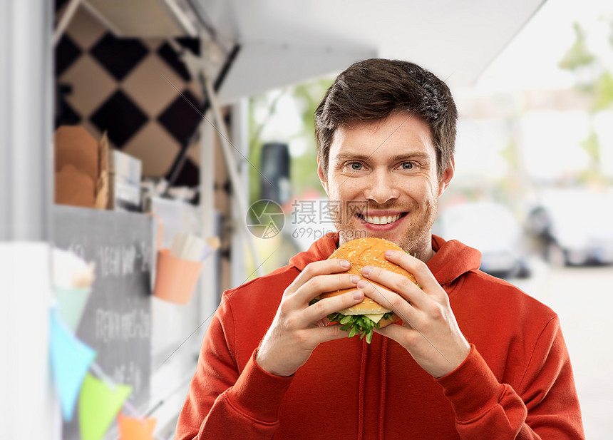 快餐,外卖人们的快乐的微笑年轻人穿着红色帽衫,街上的食品卡车上吃汉堡包快乐的年轻人食品卡车上吃汉堡包图片