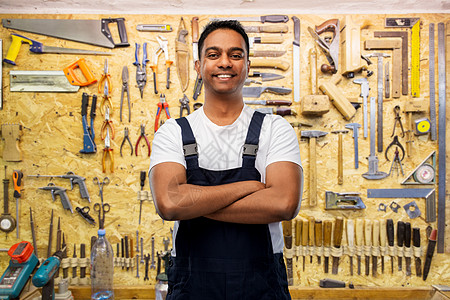 职业,建筑建筑快乐的微笑印度工人或建筑工人交叉手臂工作工具上的墙壁车间背景快乐的印度工人或建筑工人交叉手臂图片