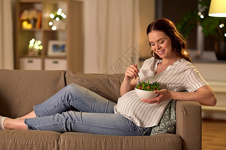 怀孕,健康的食物人们的快乐的微笑孕妇家吃蔬菜沙拉快乐微笑的孕妇家吃沙拉图片