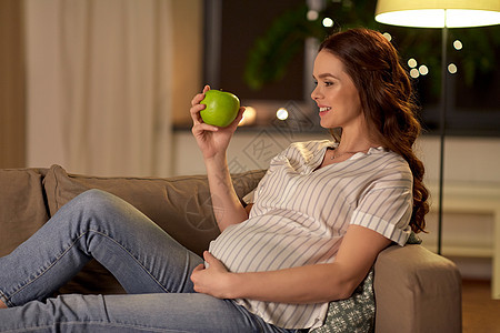 怀孕,健康的食物人们的快乐的微笑孕妇家吃绿苹果快乐的孕妇带着绿色的苹果家图片