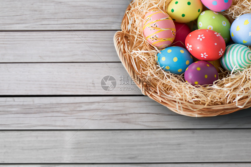 复活节,节日传统的彩色鸡蛋柳条篮子灰色木板背景篮子里彩色复活节彩蛋图片