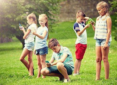 童年,增强现实,网络成瘾,技术人的群孩子或朋友与智能手机夏季公园玩游戏有智能手机的孩子夏天公园玩游戏图片