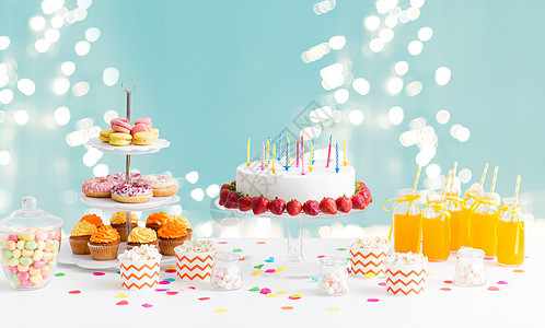 派节日生日蛋糕与蜡烛草莓,饮料食物桌子上的灯光蓝色背景生日聚会上桌子上的食物饮料图片