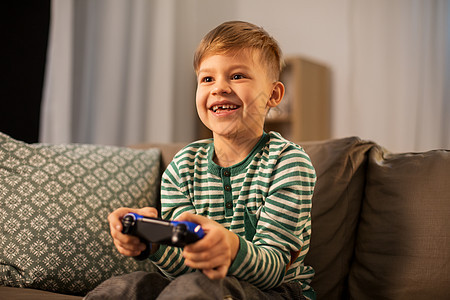 休闲,技术人的快乐的小男孩与游戏垫家里玩电子游戏晚上小男孩带着游戏垫家玩电子游戏背景图片