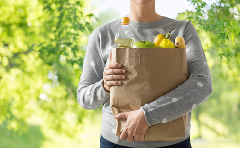购物,健康饮食生态友好的妇女与纸袋充满食物的绿色自然背景用装满食物的纸袋把女人关起来图片