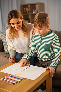 家庭休闲人的母亲小儿子用彩色铅笔纸家里画画母亲儿子家用铅笔画画图片