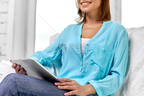 人技术休闲理念快乐的年轻女坐沙发上,家里有平板电脑家里有平板电脑的快乐女人图片