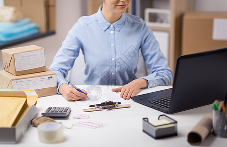 送货,邮件服务,人员装运妇女与笔记本电脑包裹盒检查表格剪贴板邮局邮局有笔记本电脑剪贴板的女人图片