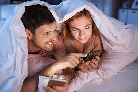 幸福夫妇在被子里玩手机图片