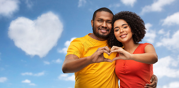 爱,情人节人的快乐的非裔美国人夫妇蓝天云彩的背景上做手势快乐的非裔美国人夫妇做手心图片