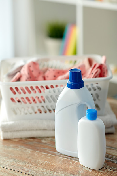 ‘~洗衣,清洗内务婴儿衣服篮子与洗涤剂护发素瓶木制桌子上家婴儿衣服放洗衣篮里,里面有洗涤剂  ~’ 的图片