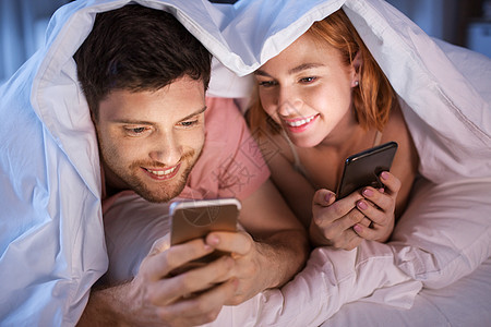 幸福夫妇在被子里玩手机图片
